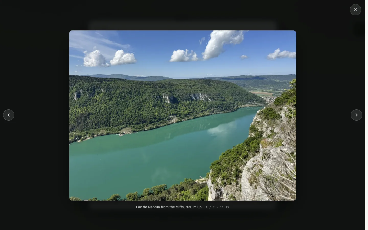 Photo viewer showing Lac de Nantua from the cliffs, with caption, image count and previous/next controls.